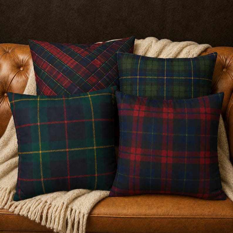 May include: Four square throw pillows featuring various plaid patterns in shades of red, green, navy blue, and yellow. The pillows are arranged in a cluster, showcasing different tartan designs with intersecting lines and color blocks.