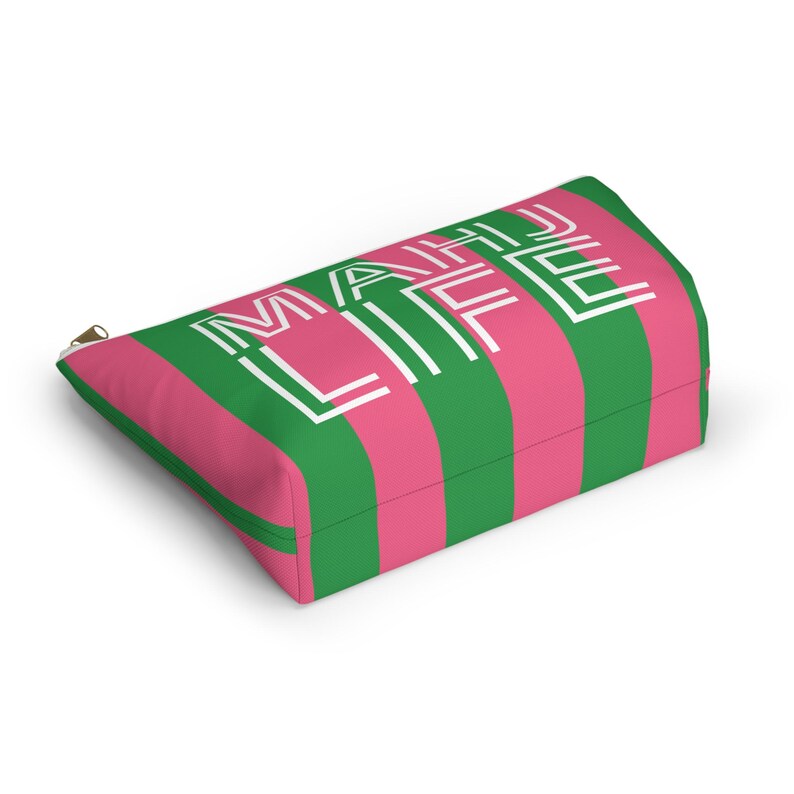 May include: A rectangular cosmetic bag with a pink and green striped pattern. The bag features the white text "MAKE LIFE" vertically. A gold zipper is visible on the side.