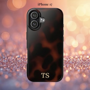 Op de afbeelding: Een iPhone 17 hoesje met een schildpadpatroon en de initialen "TS" in goud. De hoes heeft een glanzende afwerking en een uitsparing voor een dubbele lens camera. De tekst "iPhone 17" staat bovenaan de afbeelding.