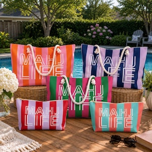 May include: A collection of striped tote bags and matching zippered pouches in various colors, including orange, pink, green, and blue. Each bag features a white rope handle and the text "MAHJ LIFE". The bags are arranged on a wooden deck near a pool.