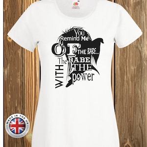Könnte beinhalten: Ein weißes kurzärmeliges T-Shirt mit einer schwarzen Silhouettengrafik einer Person mit stacheligen Haaren. Der Text lautet: You Remind Me OF THE BABE... The BABE WITH THE power. Das T-Shirt hat einen Rundhalsausschnitt und ein Etikett am Innenkragen.