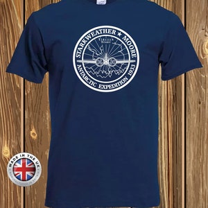 Könnte beinhalten: Marineblaues T-Shirt mit weißem, kreisförmigem Aufdruck mit dem Text "Starkweather Moore Antarctic Expedition 1933". Die Grafik zeigt eine Karte der Antarktis und ein Flugzeug. Das Shirt hat auch ein "Made in the UK"-Label.