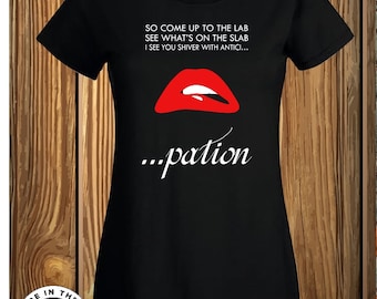 May include: A black short-sleeved t-shirt featuring a graphic of red lips and white text that reads: SO COME UP TO THE LAB SEE WHAT'S ON THE SLAB I SEE YOU SHIVER WITH ANTICI... ...pation. The shirt has a round neckline and a standard fit.