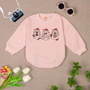 Puede incluir: Sudadera rosa de manga larga con un dise&ntilde;o de fantasma navide&ntilde;o. Los fantasmas llevan gorros de Pap&aacute; Noel y tienen un dise&ntilde;o festivo.