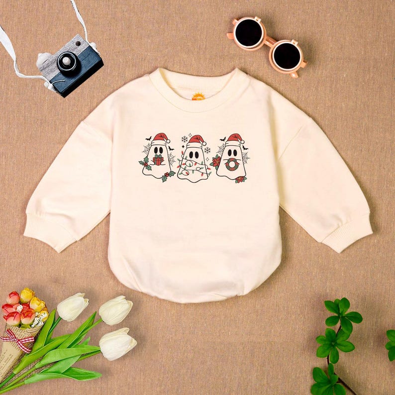 Puede incluir: Una sudadera de manga larga de color crema con un dise&ntilde;o de fantasmas navide&ntilde;os. Los fantasmas llevan gorros de Pap&aacute; Noel y tienen detalles festivos como regalos y luces.