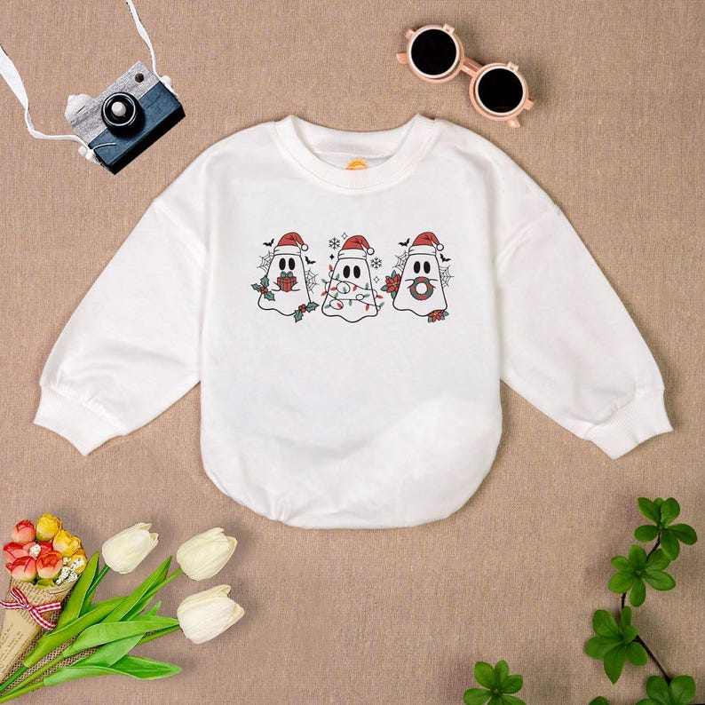 Puede incluir: Sudadera blanca de manga larga con un dise&ntilde;o de fantasma navide&ntilde;o. Tres fantasmas llevan gorros de Pap&aacute; Noel y sostienen luces de Navidad y un regalo.