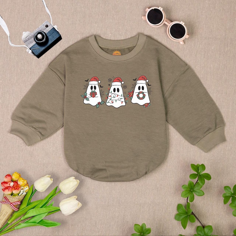 Puede incluir: Una sudadera verde de manga larga con un dise&ntilde;o de fantasmas navide&ntilde;os. Los fantasmas llevan gorros de Pap&aacute; Noel y sostienen objetos navide&ntilde;os.