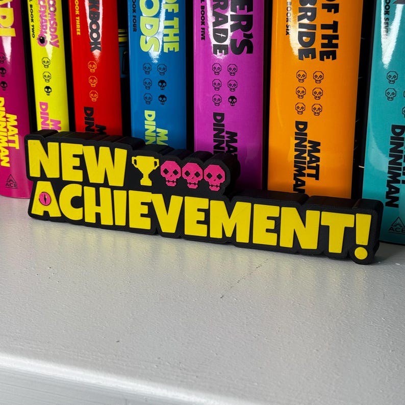 Dungeon Crawler Carl inspired “New Achievement” sign displayed on bookshelf in reading room with fantasy books