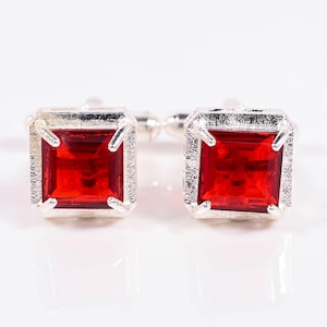 Peut inclure: Paire de boutons de manchette argentés avec des pierres rouges carrées. Les pierres sont serties dans un cadre argenté texturé. Accessoire élégant pour les tenues formelles, ces boutons de manchette ajoutent une touche de raffinement.
