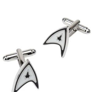 Może przedstawiać: Para srebrnych spinek do mankietów z insygniami Starfleet Command z Gwiezdnej Floty. Spinki do mankietów mają białe tło z czarną obwódką i czarną gwiazdą pośrodku. Spinki do mankietów są wykonane z metalu.
