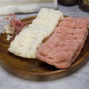 May include: Two soft, plush headbands in a wooden bowl. One headband is white and the other is pink.
