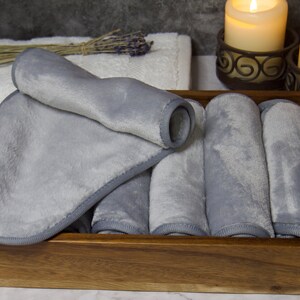 May include: A wooden box filled with six gray microfiber cloths. The cloths are rolled up and have a stitched edge.