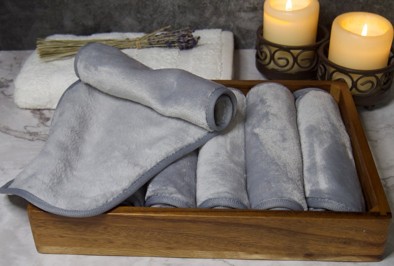May include: A wooden box filled with six gray microfiber cloths. The cloths are rolled up and have a stitched edge.