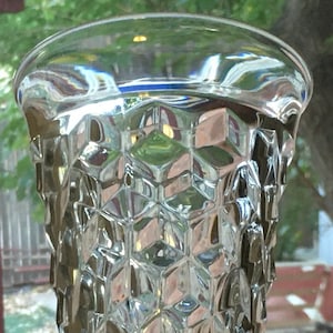 May include: A clear glass vase with a diamond-shaped pattern. The vase is empty and has a wide mouth.