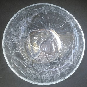 May include: A clear glass bowl with an etched floral design. The bowl features a large flower in the center with smaller flowers and leaves surrounding it.