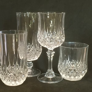 May include: Four clear glass drinking glasses with a diamond pattern. The glasses are all different sizes and shapes.