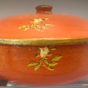 以下が含まれることがあります： オレンジとゴールドのフローラルパターンが付いた蓋付きボウル。ボウルは金属製で、上部にゴールドのトリムが施されています。