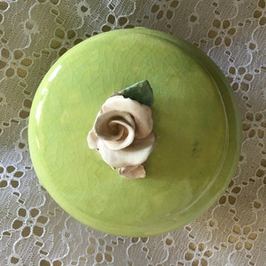 May include: A green ceramic trinket box with a white porcelain rose on the lid.