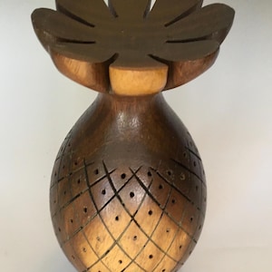 May include: A wooden vase with a pineapple design and a flower-shaped top. The vase is carved with a pattern of holes and lines.