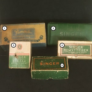 May include: Five vintage Singer sewing machine attachments in boxes. The boxes are green and yellow with the Singer logo and text. The attachments include a buttonhole worker, a hemstitcher, and a zigzag attachment.