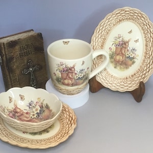 Peut inclure: Un ensemble de tasses et soucoupes à thé en céramique avec un motif tissé et un lapin tenant un panier de fleurs. Les tasses et soucoupes sont décorées d'un motif floral et de papillons.