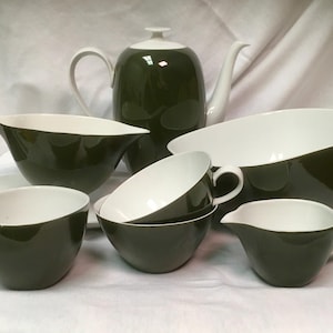 May include: A complete olive green and white ceramic tea set. The set includes a teapot, serving bowls, cups, and a creamer. The tea set has a glossy finish and a modern design. The interior of the cups and bowls are white.