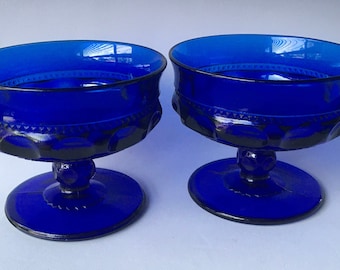 May include: Two cobalt blue glass dessert cups with a pedestal base and a textured design.