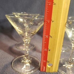 May include: Set of four clear glass martini glasses with a starburst pattern etched into the glass. The glasses are approximately 3.5 inches tall.