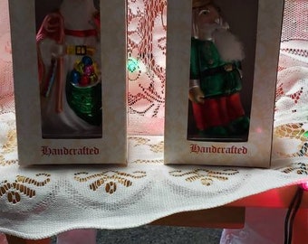 May include: Two Turn of the Century Old World Glass Christmas ornaments in their boxes. The ornaments are handcrafted and feature a Santa Claus and a man in a green suit.