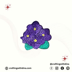 May include: A purple flower-shaped patch with yellow accents and green leaves. The patch has a textured appearance and is likely embroidered. The image also includes the text "craftingwithdina.com" and social media icons.