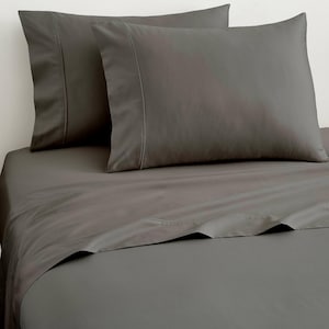 May include: A set of dark gray bed sheets and two matching pillowcases. The pillowcases feature a wide hem detail along the opening, and the flat sheet is draped smoothly over the bed, showcasing a solid, uniform charcoal color throughout.