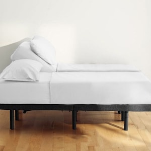 May include: A white adjustable bed frame with a black base and legs. The bed is made up with white sheets and pillows.