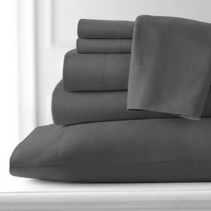 May include: A stack of grey bed sheets and pillowcases. The sheets are made of a soft, smooth fabric.
