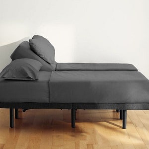 May include: A gray adjustable bed frame with a gray mattress and two pillows. The bed frame has a black metal base and legs.