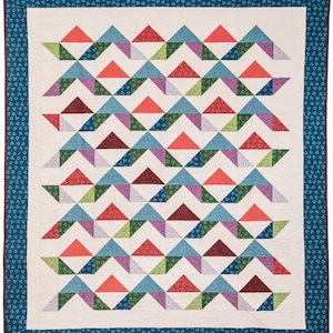 May include: A quilt with a geometric pattern of triangles in shades of red, blue, green, and purple. The triangles are arranged in a repeating pattern, creating a wave-like effect. The quilt is bordered with a blue fabric with a white heart pattern.