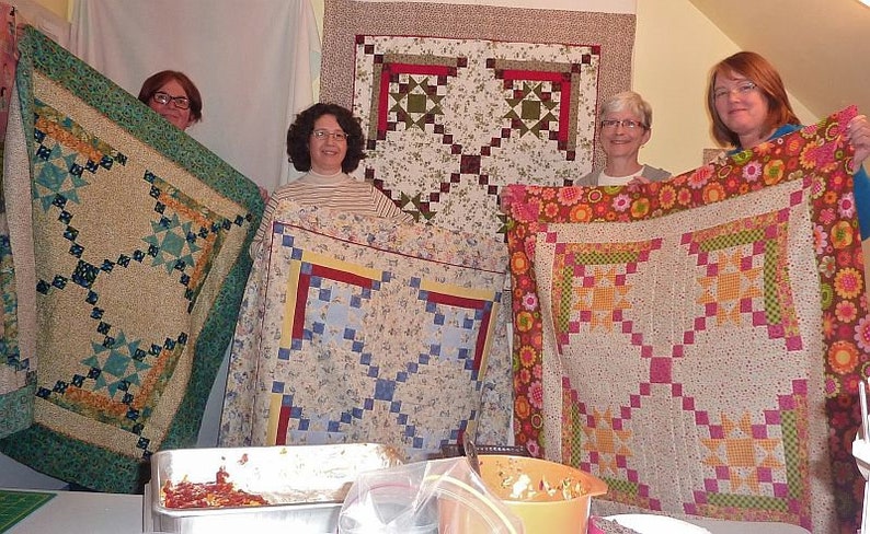 Three Mystery Quilters holding up their quilt tops made from the Appian Way Quilt Pattern.