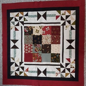 Made by Deb, This Round the Mountain Mini-Quilt pattern is created with a charm packet of fabrics and a border.