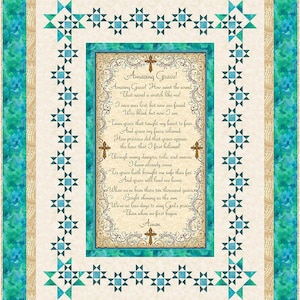 May include: A quilted wall hanging with the hymn "Amazing Grace" at its centre, framed by a decorative border and crosses. The quilt features a teal, cream, and tan colour scheme with star-shaped accents. The text is clearly visible.