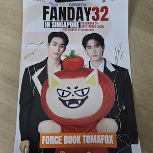 Pode incluir: Um cartaz promocional para o GMMTV FANDAY 32 em Singapura, a 5 de setembro de 2026, no The Theatre at Mediacorp. Apresenta duas pessoas em fatos pretos, assinaturas a tinta preta e uma grande peluche chamada Force Book Tomafox.