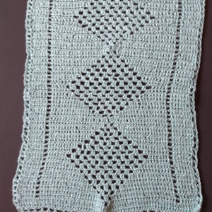 May include: A light blue crocheted doily with a diamond pattern.