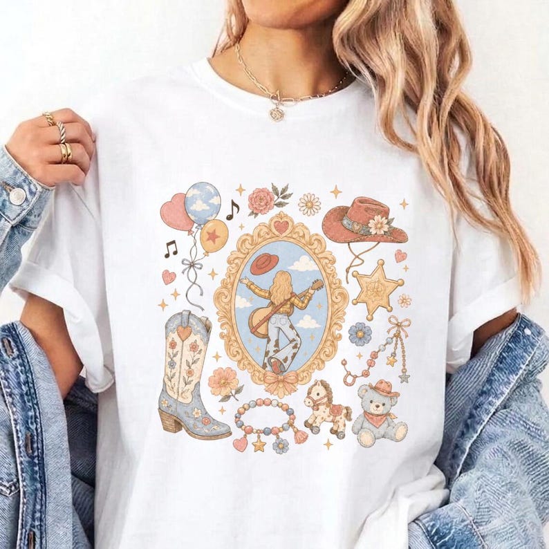 May include: A white t-shirt featuring a central graphic print of a person playing a guitar inside an ornate gold frame, surrounded by illustrations of a cowboy hat, a western boot, a teddy bear, balloons, flowers, and a star-shaped badge.