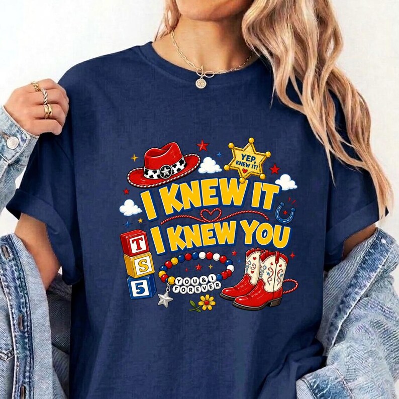 Puede incluir: Una camiseta azul marino con un estampado gr&aacute;fico que incluye un sombrero de vaquero rojo, una estrella de sheriff amarilla con el texto YEP, KNEW IT!, tres bloques alfab&eacute;ticos apilados T, S, 5, una pulsera de cuentas y botas de vaquero rojas con el texto I KNEW IT I KNEW YOU.