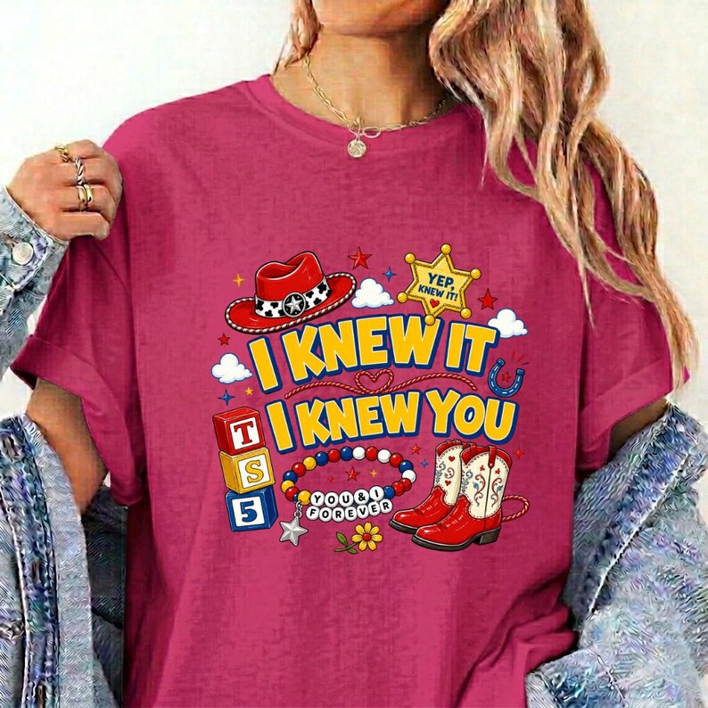 Puede incluir: Una camiseta magenta con un estampado gr&aacute;fico que incluye un sombrero de vaquero rojo, una estrella de sheriff amarilla con el texto YEP, KNEW IT, bloques de letras coloridos, una pulsera de cuentas con el texto YOU & I FOREVER y botas vaqueras rojas.