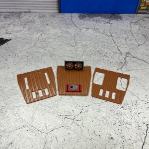 Pode incluir: Tr&ecirc;s tapetes de ch&atilde;o de pl&aacute;stico castanho para um carro modelo, com um detalhe de motor vermelho e preto no centro.