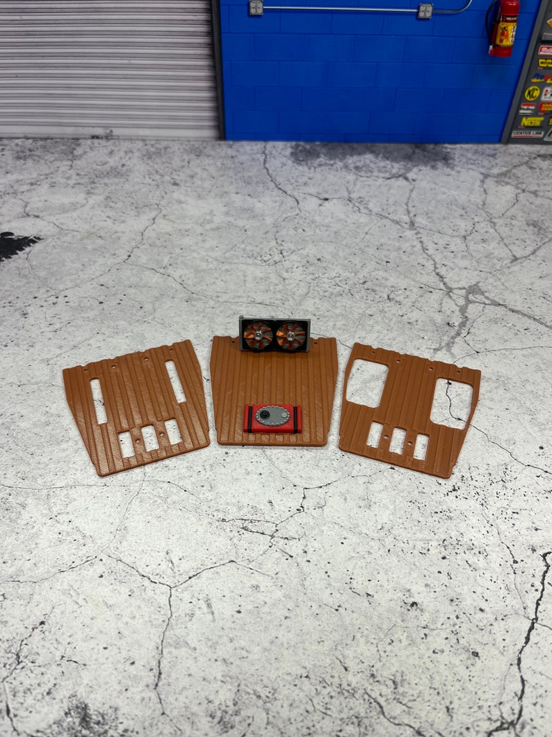 Pode incluir: Tr&ecirc;s tapetes de ch&atilde;o de pl&aacute;stico castanho para um carro modelo, com um detalhe de motor vermelho e preto no centro.