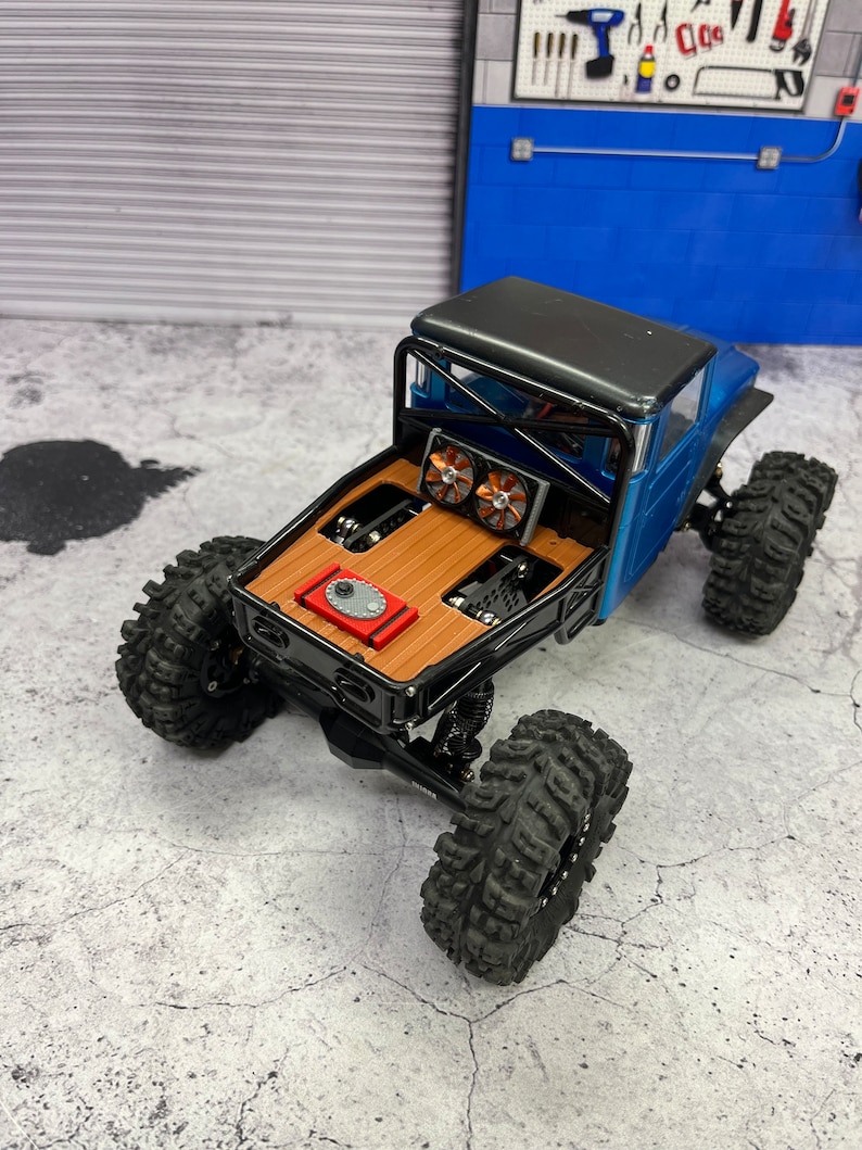 Pode incluir: Um caminh&atilde;o de brinquedo azul e preto com uma ca&ccedil;amba de madeira e dois ventiladores na parte de tr&aacute;s. O caminh&atilde;o est&aacute; sentado em uma superf&iacute;cie de concreto cinza.
