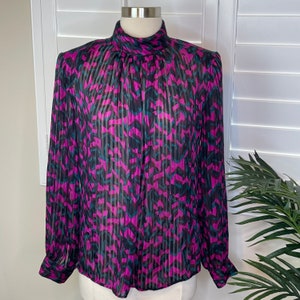 May include: A sheer, long-sleeved blouse with a high neck and a geometric print in shades of pink, black, and teal.