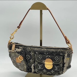 May include: A black and grey denim Louis Vuitton handbag with a gold zipper and hardware. The bag has a distressed look with frayed edges and patchwork details.