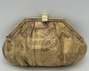 Könnte beinhalten: Eine goldfarbene Clutch aus Schlangenleder mit einem goldfarbenen Verschluss.
