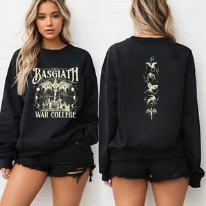 May include: Black sweatshirt with the text "BASGIATH WAR COLLEGE" in a stylized font, featuring a graphic of a castle, dragons, and celestial elements. The back of the sweatshirt has a vertical design with dragon illustrations.
